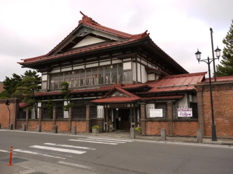赤い屋根の和洋折衷の大きな屋敷と、れんがの塀
